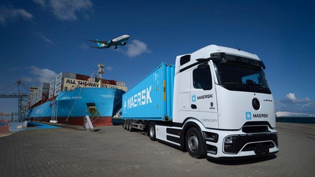 A large truck parked beside a massive container ship at a busy port, showcasing maritime logistics and transportation.