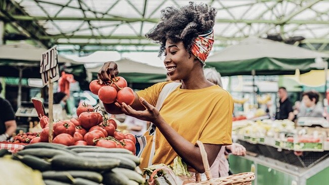 Young African woman buying FMCG perishable goods at the market.