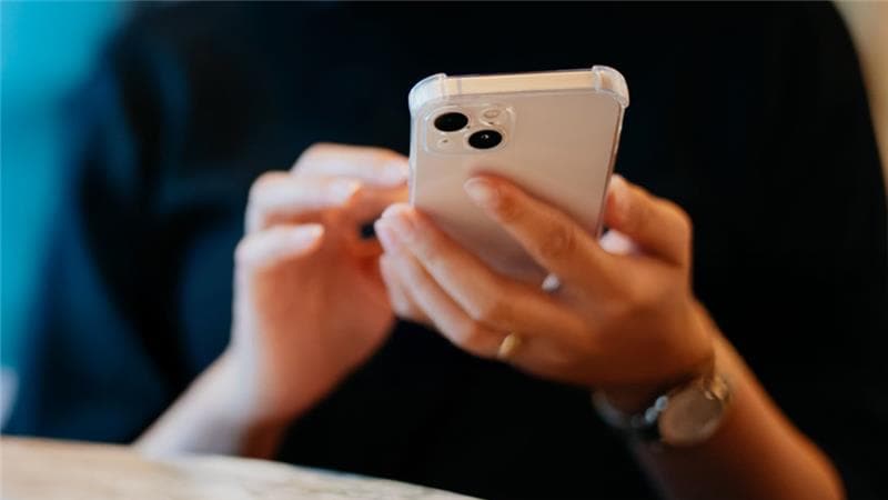 A woman is focused on her cell phone, engaged in a conversation or browsing content.