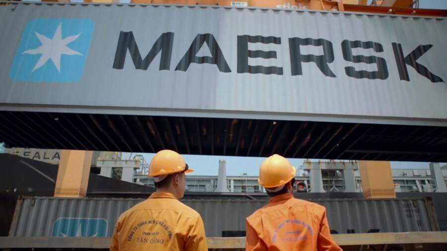 A warehouse worker in a reflective safety vest uses a digital tablet to manage inventory, standing in an aisle surrounded by stacked shelves filled with boxes.