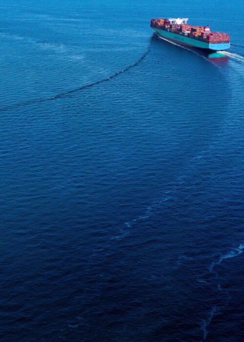 Maersk container ship sailing across the ocean with cargo.