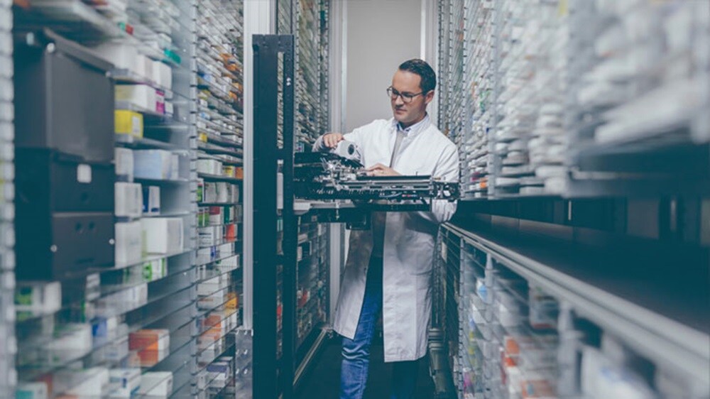 Healthcare supply chain – A man wearing lab coat looking at a product in a pharmaceutical store.