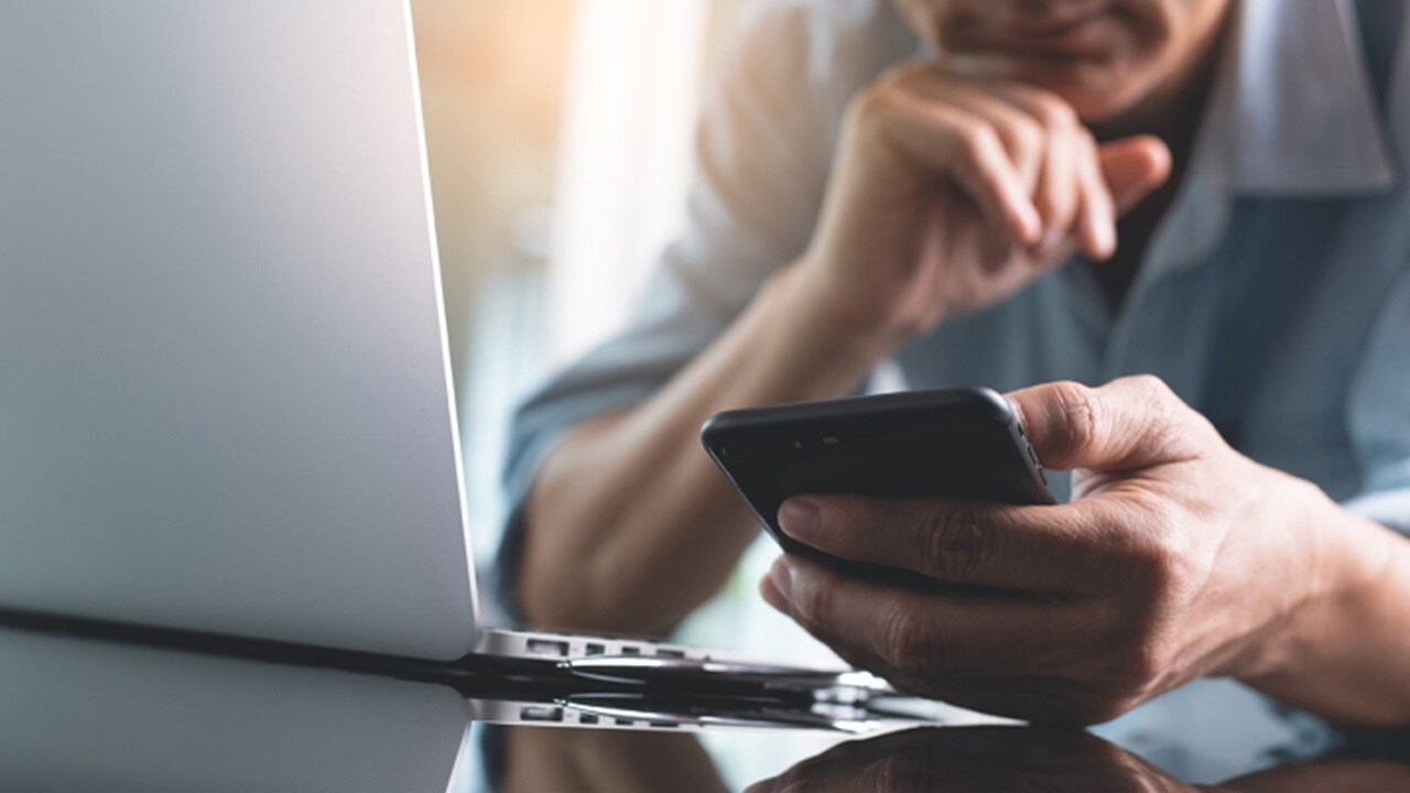 A concerned man looking at his mobile and trying to figure out to book consignments on his own.