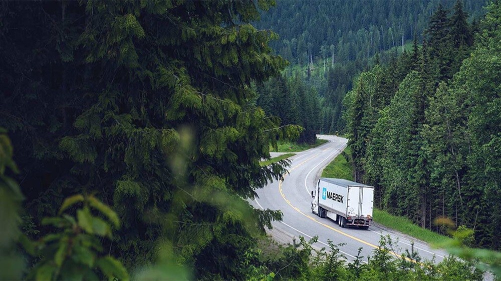 Maersk truck transporting cargo through scenic forest route, highlighting sustainable road freight logistics solutions