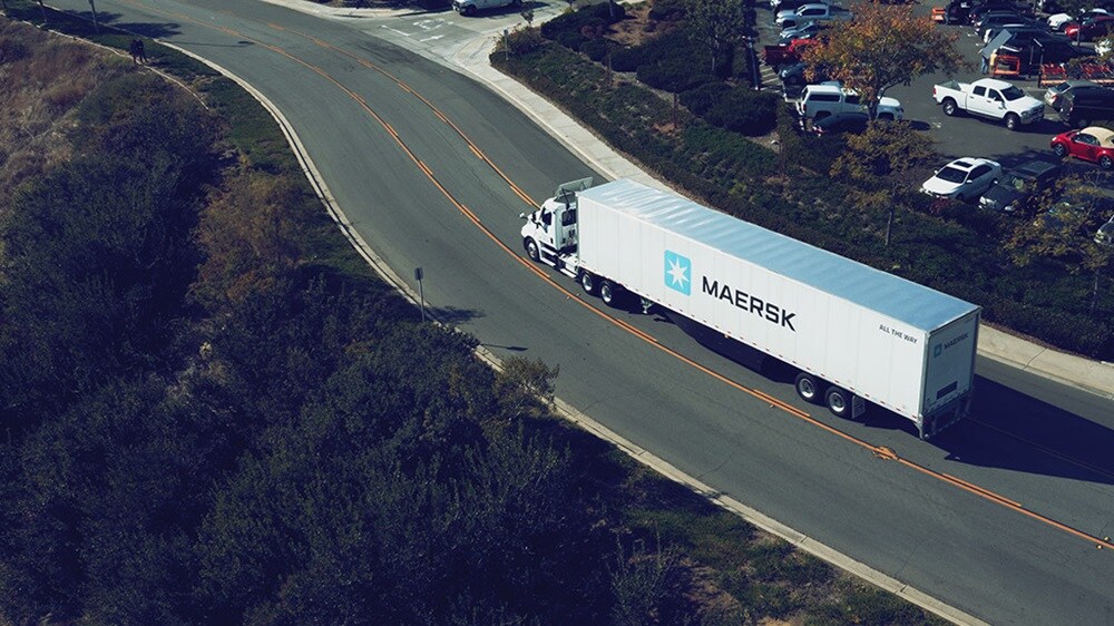 A Maersk shipping container truck on a highway