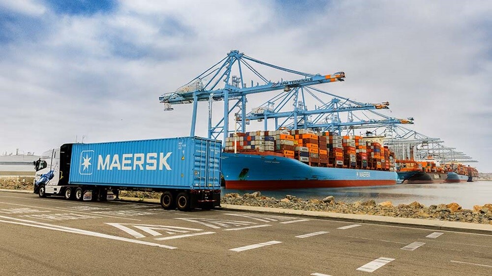 Maersk container truck at a port terminal beside a Maersk cargo ship being loaded with containers